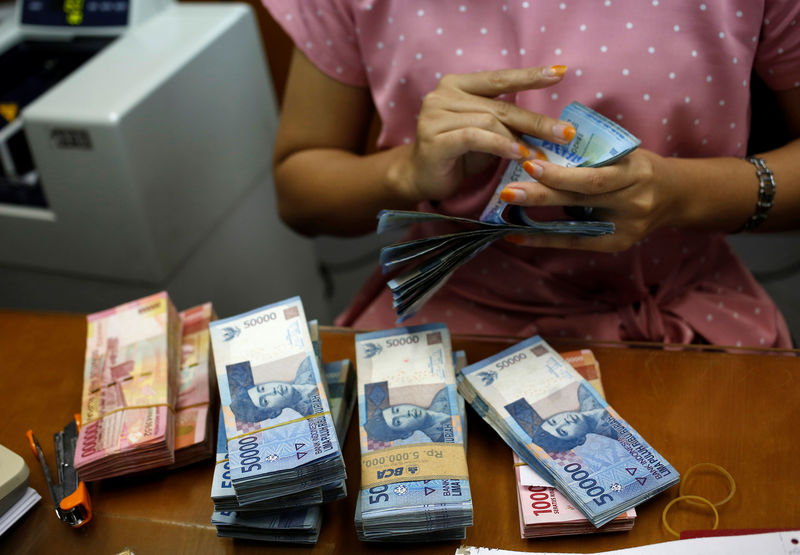 © Reuters. A teller counts Indonesian rupiah bank notes at a money changer in Jakarta