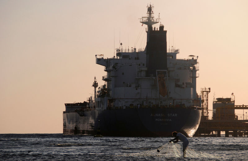 © Reuters. FILE PHOTO: Fisherman pulls in his net as an oil tanker is seen at the port in the northwestern city of Duba