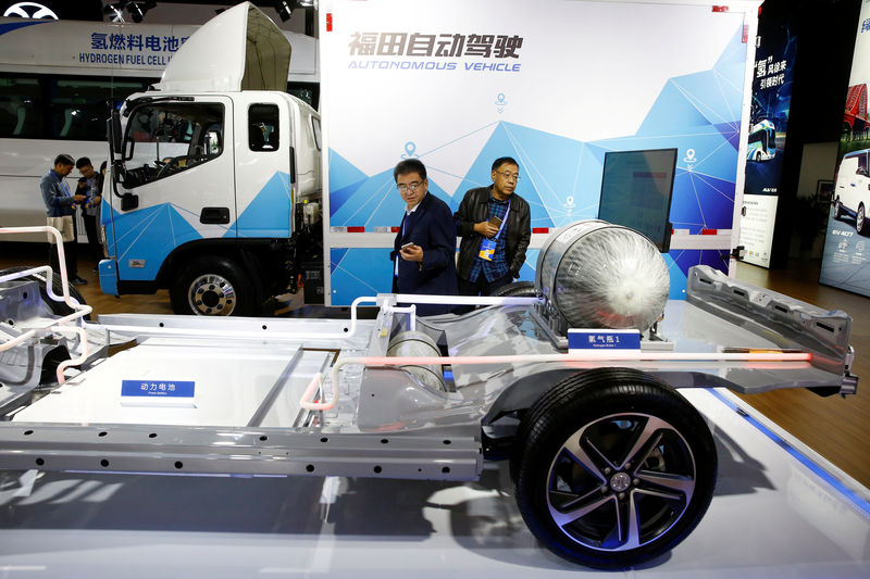 © Reuters. FILE PHOTO: Visitors looks at the frame of an electric vehicle next to a Foton autonomous truck at the stall of the BAIC Group automobile maker at the IEEV New Energy Vehicles Exhibition in Beijing