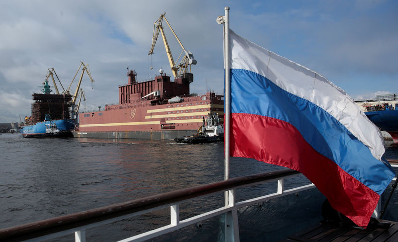 © Reuters. Флаг России на фоне плавучей атомной теплоэлектростанции "Академик Ломоносов" в Санкт-Петербурге