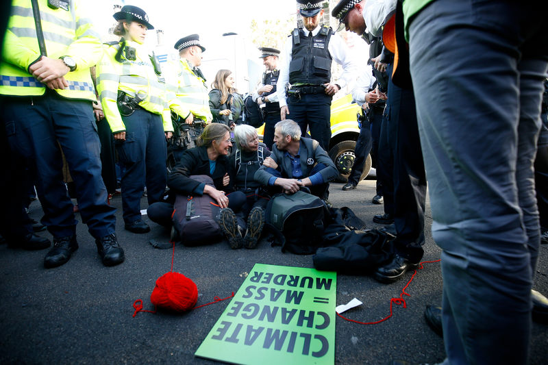 © Reuters. Police officers stand around protesters sitting in the road outside the Houses of Parliament during a demonstration against fracking, in London