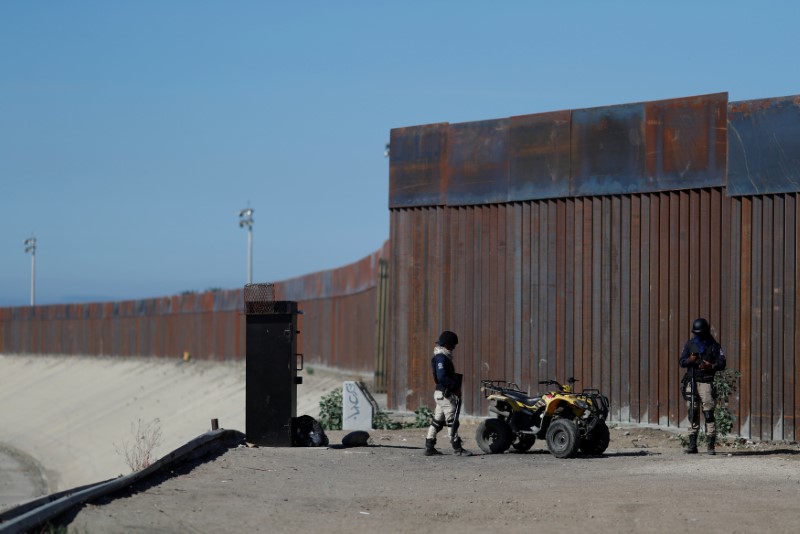 © Reuters. Private security guards stand guard in front of the border fence between Mexico and United States, in Tijuana