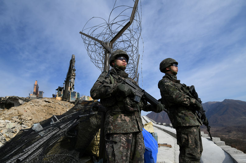 © Reuters. FILE PHOTO: South Korean soldiers stand guard as construction equipment destroy a guard post in the Demilitarized Zone dividing the two Koreas in Cheorwon
