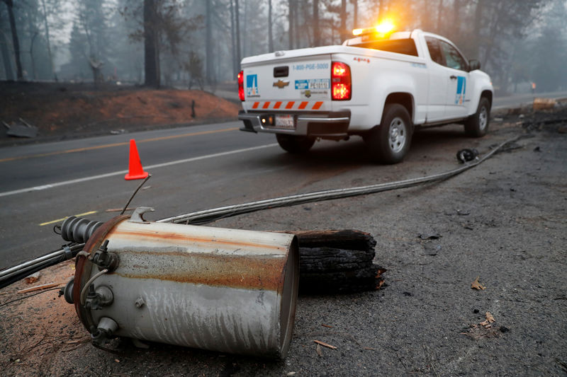 © Reuters. An electricity pole damaged by the Camp Fire lies near a Pacific Gas & Electric truck in Paradise