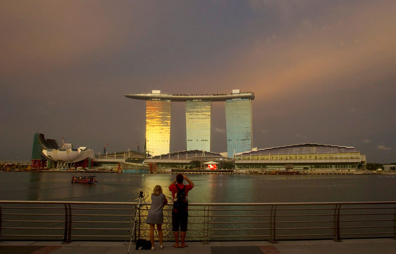 © Reuters. File picture shows tourists standing at a promenade across the water from the Marina Bay Sands integrated resort in Singapore