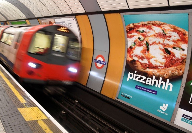 © Reuters. A train passes an advertisement for a food delivery company at Green Park underground station in London Britain