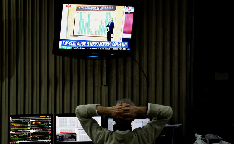 © Reuters. A man watches news on TV as he works on the floor of the Buenos Aires Stock Exchange