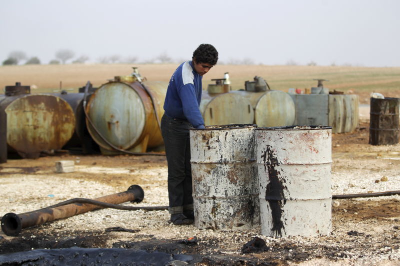 © Reuters. A youth works at a makeshift oil refinery site in Marchmarin town, southern countryside of Idlib, Syria