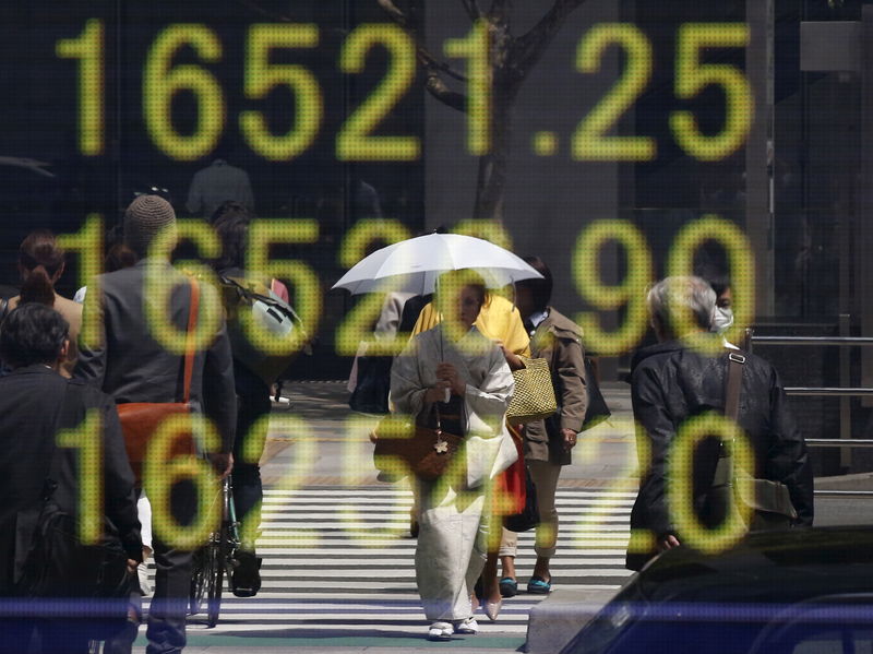 © Reuters. FILE PHOTO - Woman clad in a kimono is reflected in an electronic board displaying Japan's Nikkei share average outside a brokerage in Tokyo