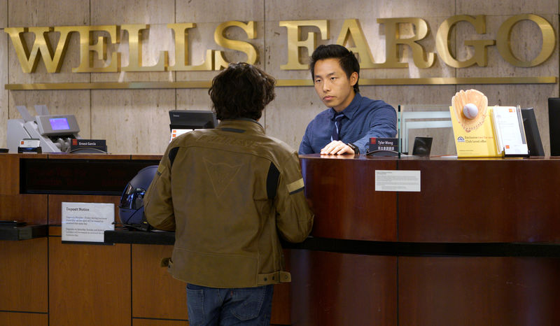 © Reuters. Bank Teller Tyler Wong talks to a customer at the Wells Fargo bank in Denver