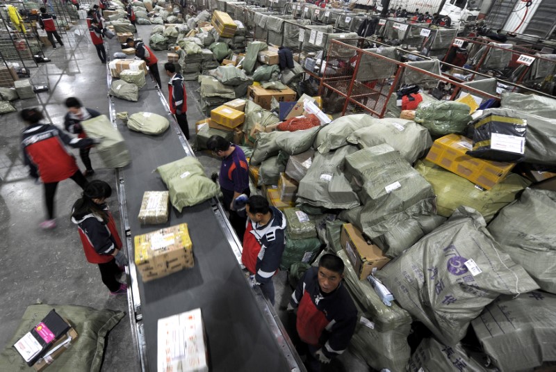 © Reuters. Workers sort packages at a logistics hub in Jinan