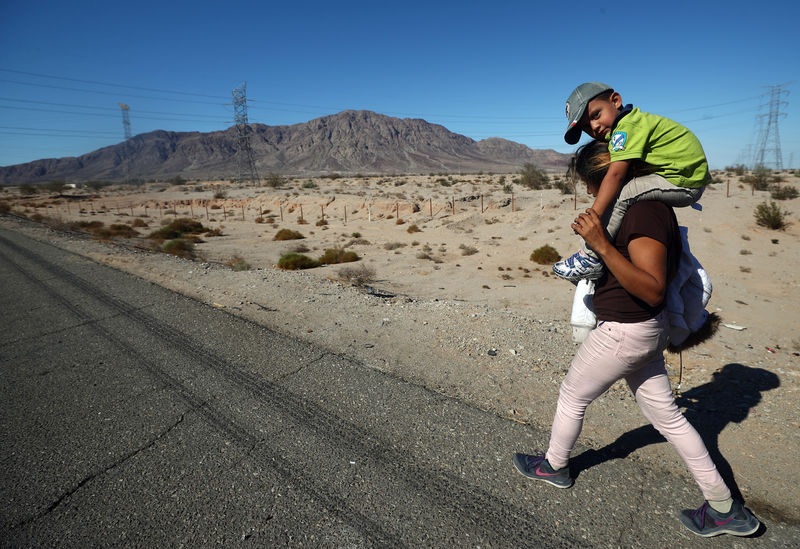 © Reuters. Imigrante de Honduras leva filho nas costas durante caravana a caminho dos Estados Unidos