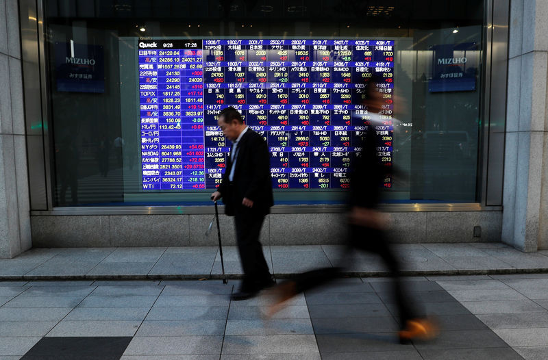 © Reuters. Passersby walk past in front of an electronic stock quotation board outside a brokerage in Tokyo