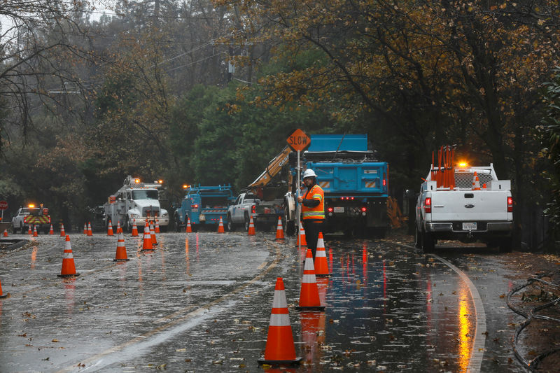 © Reuters. Equipes trabalham sob chuva para reparar danos provocados por incêndio em Paradise, na Califórnia