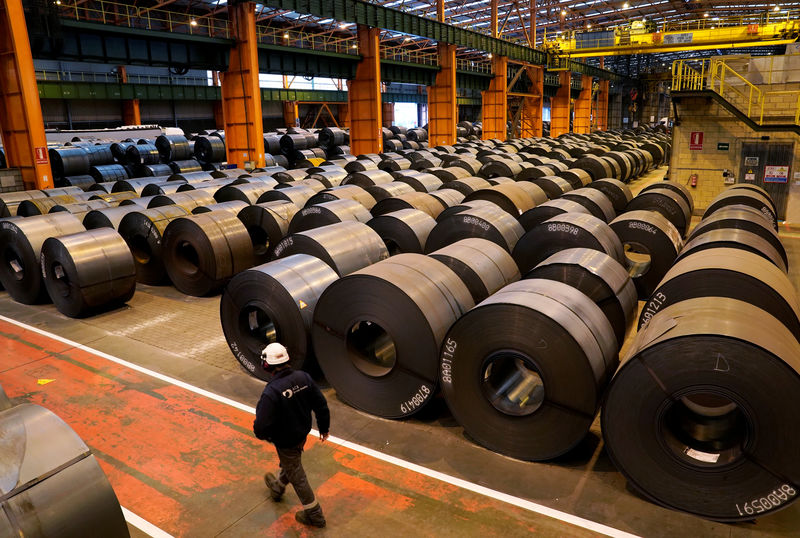 © Reuters. FILE PHOTO: A worker walks past steel rolls at the ArcelorMittal steel plant in Sestao