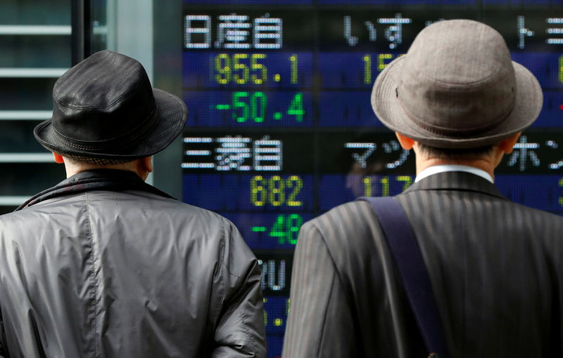 © Reuters. Men look at a stock quotation board showing share prices of Nissan Motor Co and Mitsubishi Motors outside a brokerage in Tokyo