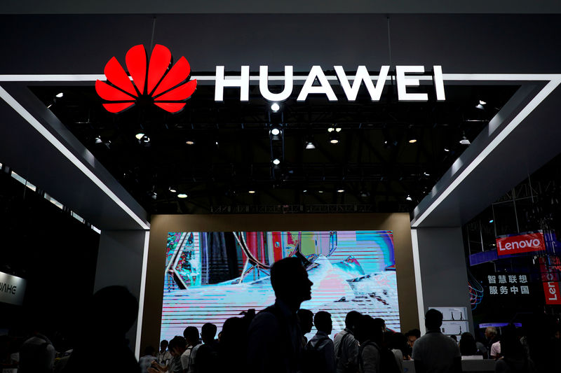 © Reuters. FILE PHOTO - People walk past a sign board of Huawei at CES (Consumer Electronics Show) Asia 2018 in Shanghai