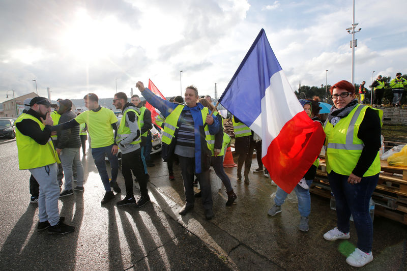 © Reuters. A demonstrator wearing yellow vests, a symbol of a French drivers' protest against higher fuel prices,  holds a French flag as they block the access to the Total biodiesel refinery at La Mede