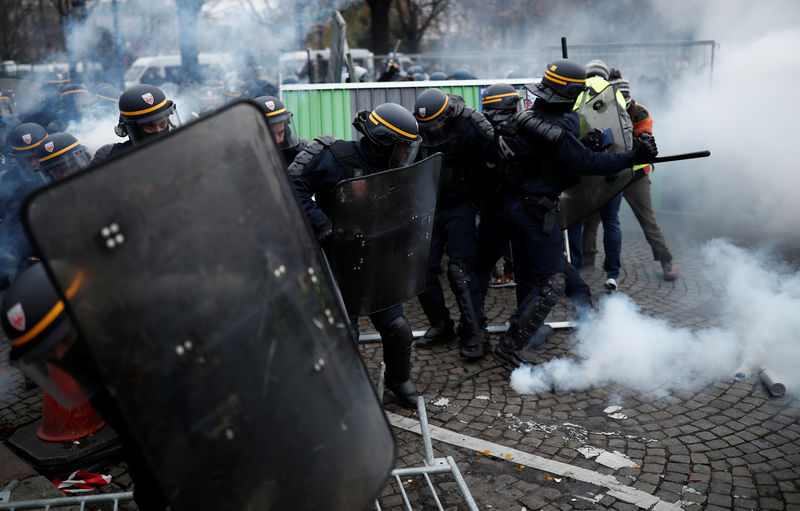 © Reuters. Police officers fire a tear gas during protests against higher fuel prices, on the Champs-Elysee in Paris