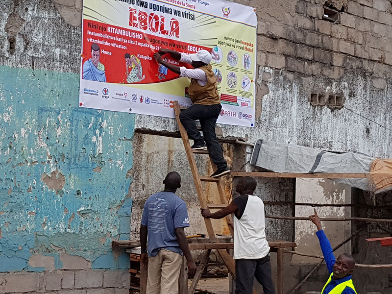 © Reuters. Foto de archivo de un trabajador colgando un poster explicativo sobre el Ébola en Tchomia, Congo
