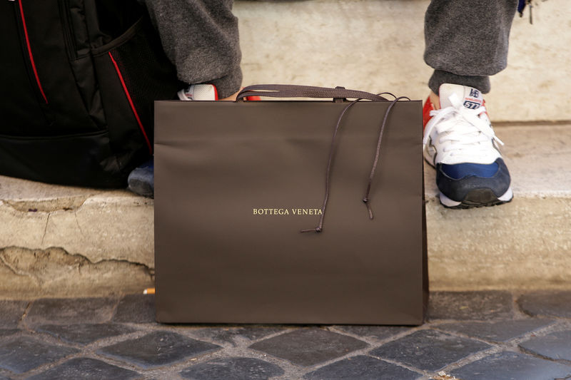 © Reuters. FILE PHOTO: A man sits next a Bottega Veneta bag in downtown Rome