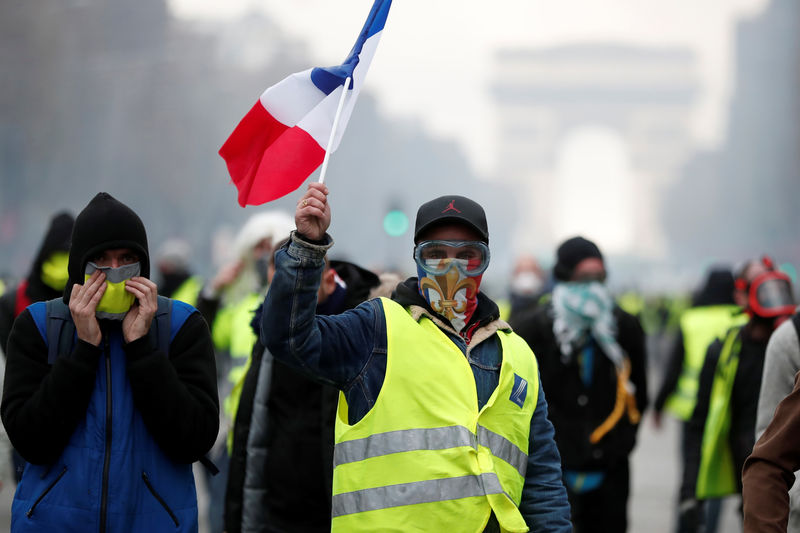 © Reuters. Masked protesters wearing yellow vests, a symbol of a French drivers' protest against higher fuel prices, take part in a demonsgtraion on the Champs-Elysees in Paris