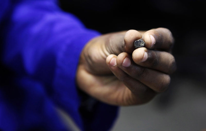 © Reuters. A Zimbabwean worker holds a piece of rough diamond from the country's Marange diamond fields, inside a polish and cutting shop in Harare