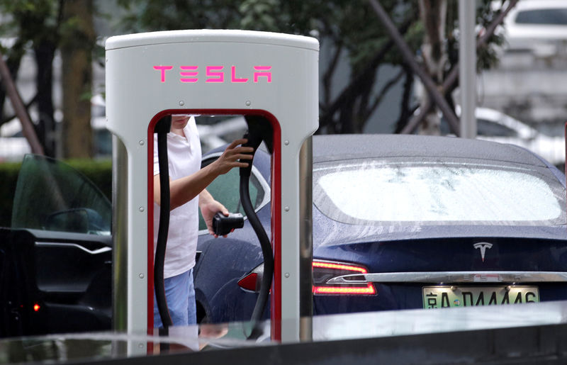 © Reuters. FILE PHOTO: A man finishes to charge his Tesla car at  a charging point in Beijing