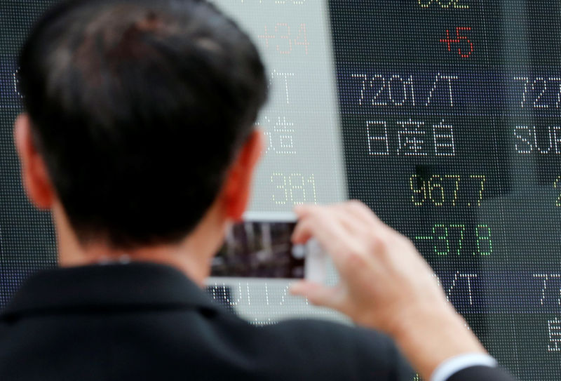 © Reuters. Мужчина фотографирует котировки акций в Токио