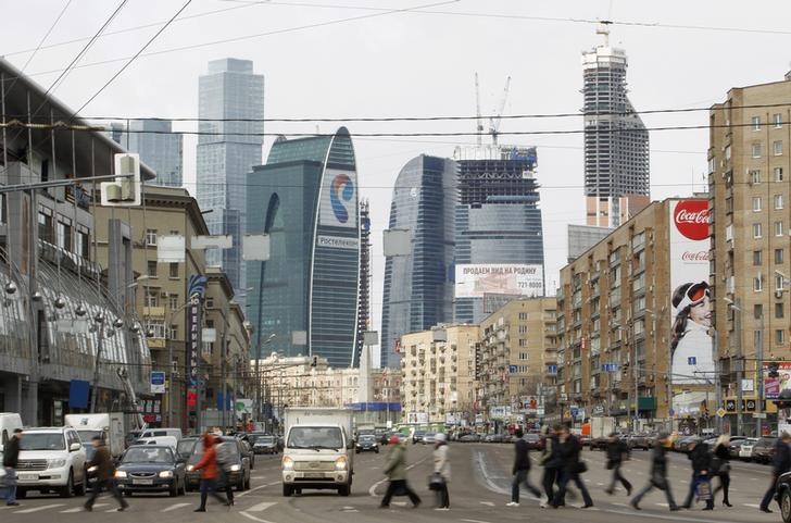 © Reuters. People cross a road, with the Vostok or East tower, part of the Federation complex in the "Moscow City" business district, seen in the background in Moscow