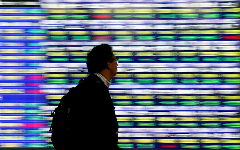 © Reuters. A man walks past an electronic stock quotation board outside a brokerage in Tokyo