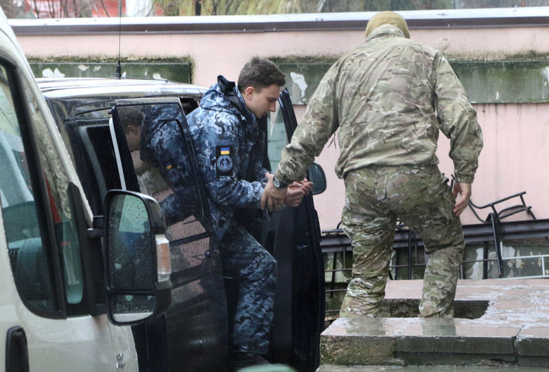 © Reuters. A member of Russia's FSB security service escorts a detained Ukrainian navy sailor before a court hearing in Simferopol