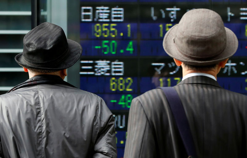 © Reuters. Прохожие у электронного табло с котировками японских акций в Токио