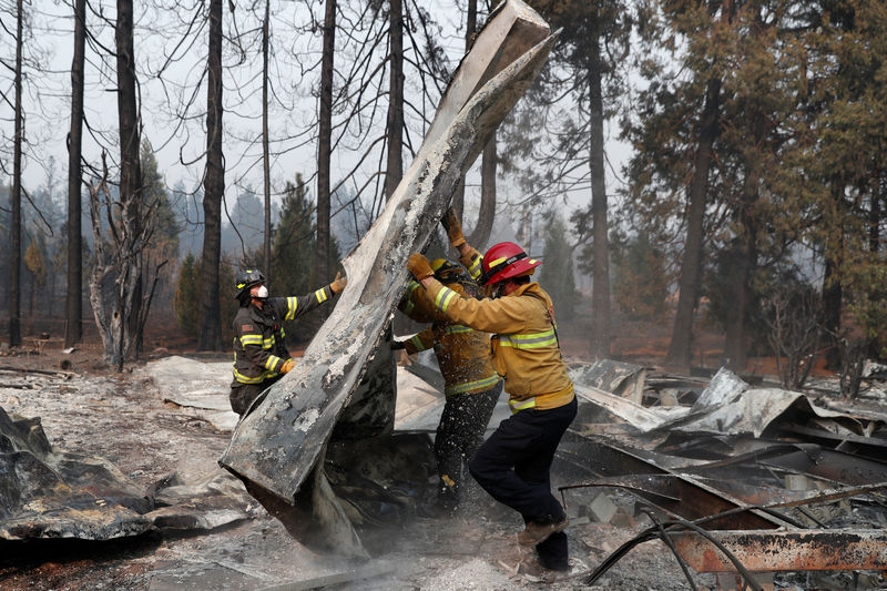 © Reuters. Bomberos mueven escombros mientras recuperan restos humanos de un remolque destruido por el Camp Fire en Paradise