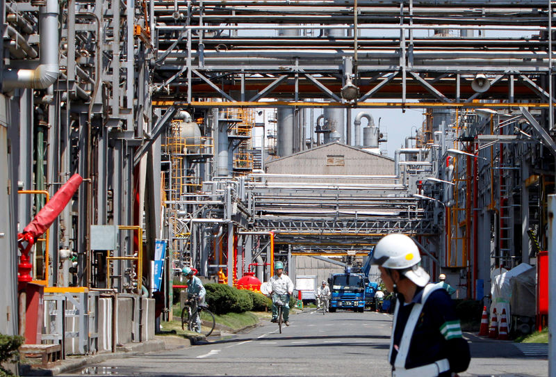 © Reuters. FILE PHOTO: Workers ride bicycles as a guard looks on at a factory in Keihin industrial zone in Kawasaki