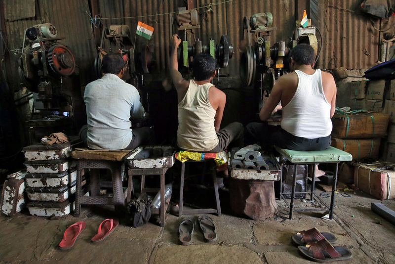 © Reuters. Workers operate metal cutting machines inside a workshop at an industrial area in Mumbai