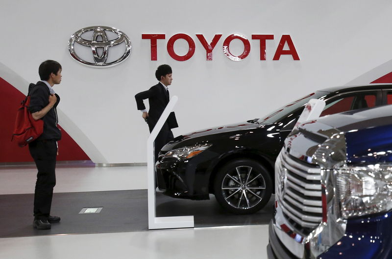 © Reuters. People walk under a logo of Toyota Motor Corp at the company's showroom in Tokyo