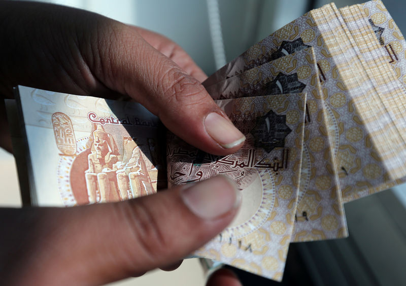 © Reuters. A man counts Egyptian pounds outside a bank in Cairo