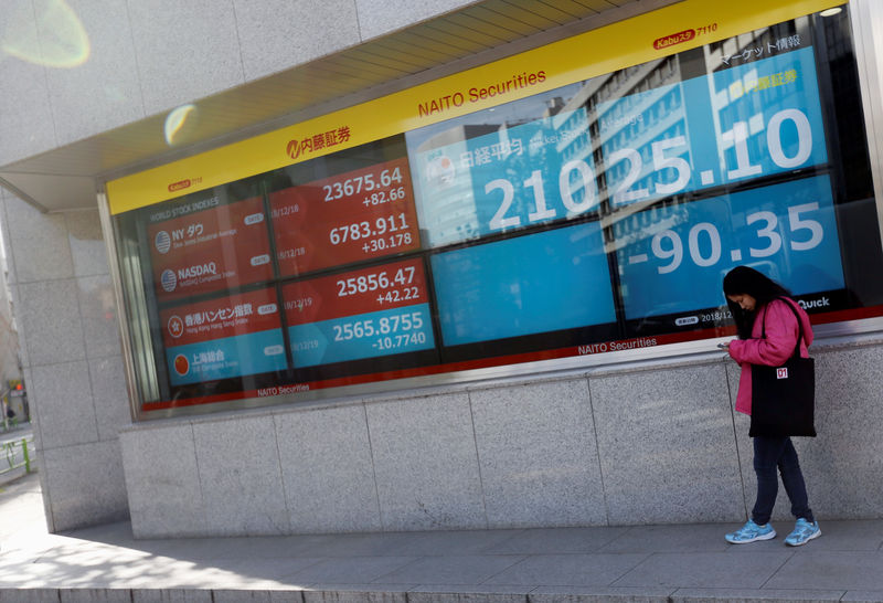 © Reuters. A woman stands in front of a screen displaying Japan's Nikkei share average, U.S. and other countries' stock market indicators outside a brokerage in Tokyo