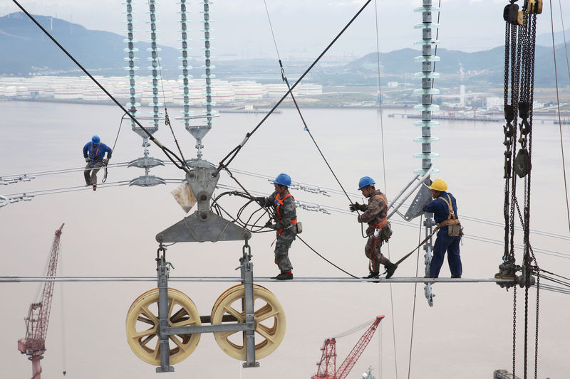 © Reuters. Men work on cables connecting power transmission towers in Zhoushan