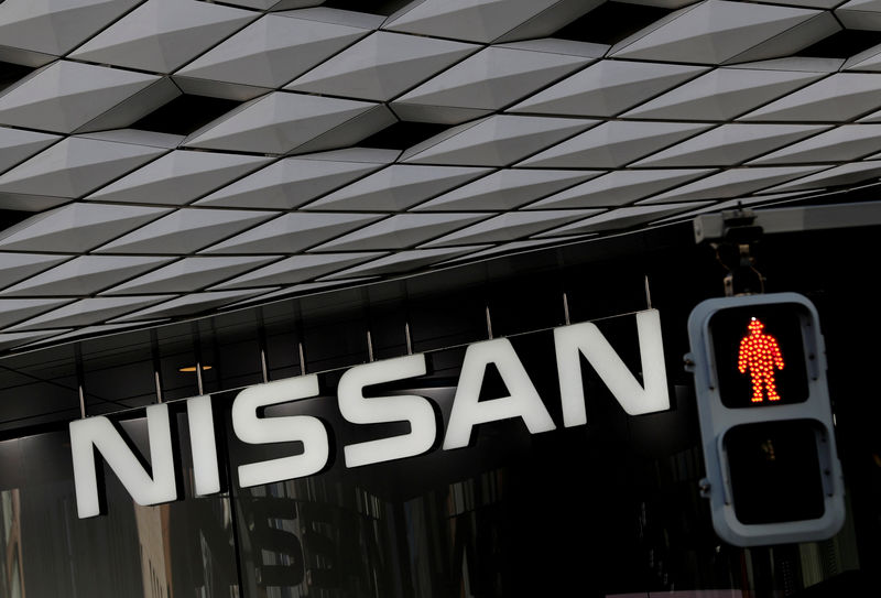 © Reuters. FILE PHOTO: Nissan's signboard is seen behind a traffic sign at a showroom in Tokyo