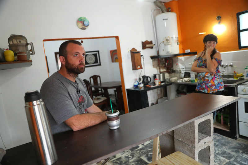 © Reuters. Fabian Pennella, a former government worker who lost his job a few months ago, and his wife talk to Reuters in the house where he and his family moved into temporarily, in Buenos Aires