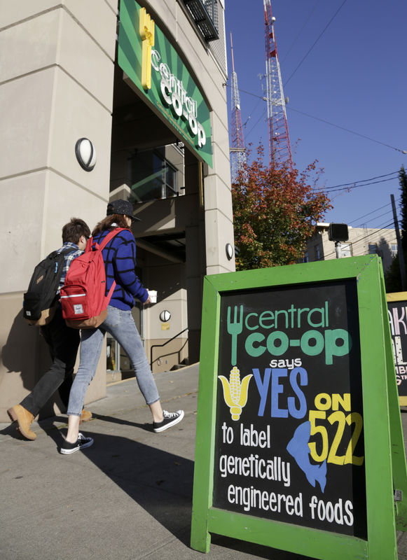 © Reuters. People walk past a sign supporting a ballot initiative in Washington state that would require labeling of foods containing genetically modified crops at the Central Co-op in Seattle, Washington