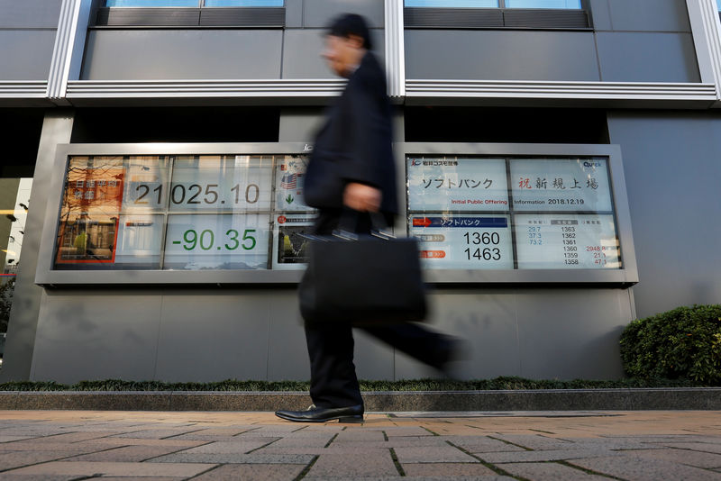 © Reuters. A man walks past in front of a stock quotation board showing the price of the SoftBank Corp. and Nikkei share average outside a brokerage in Tokyo