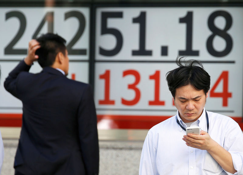 © Reuters. Men stand in front of an electronic board showing Japan's Nikkei average outside a brokerage in Tokyo