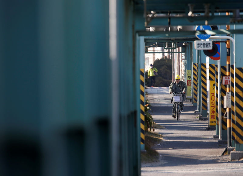 © Reuters. A worker cycles near a factory at the Keihin industrial zone in Kawasaki