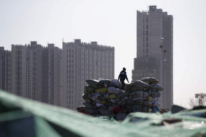 © Reuters. FILE PHOTO: A man works near apartment blocks under construction on the outskirts of Beijing, China
