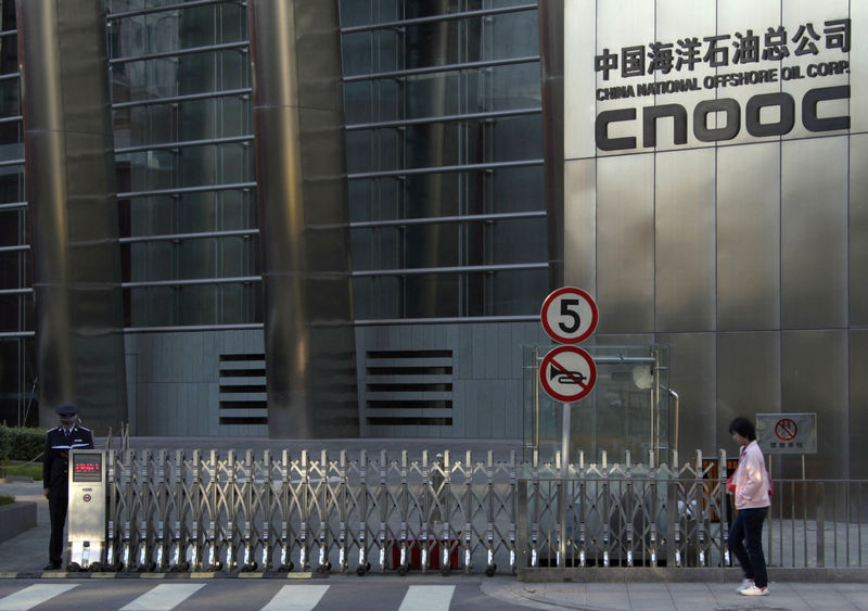 © Reuters. A woman walks past the entrance of the headquarters of China National Offshore Oil Corp in Beijing