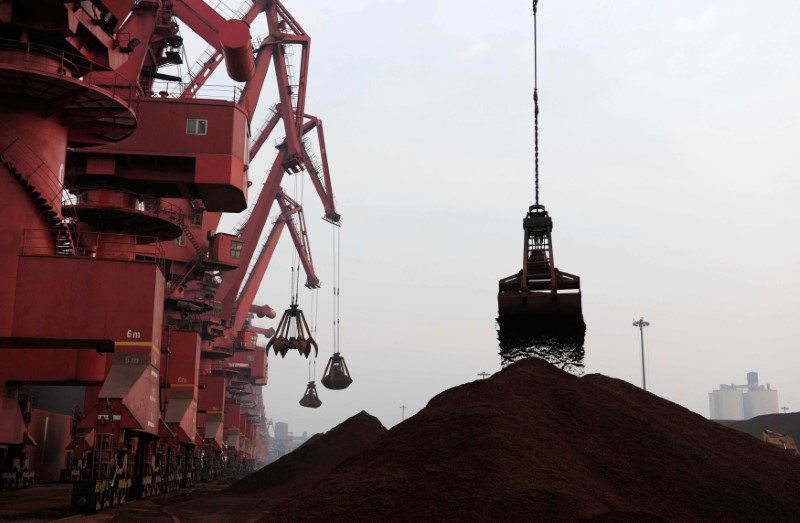 © Reuters. FILE PHOTO: Cranes unload iron ore from a ship at a port in Rizhao