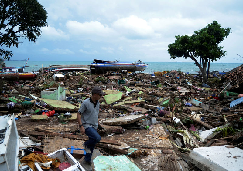 © Reuters. Un habitante local camina mientras busca sus artículos entre los escombros tras el paso de un tsunami en el distrito de Rajabasa en el sur de Lampung, Indonesia
